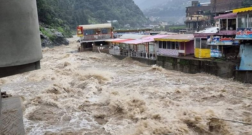 Raging muddy floodwaters surge past riverside buildings in Gilgit-Baltistan during heavy monsoon rains.