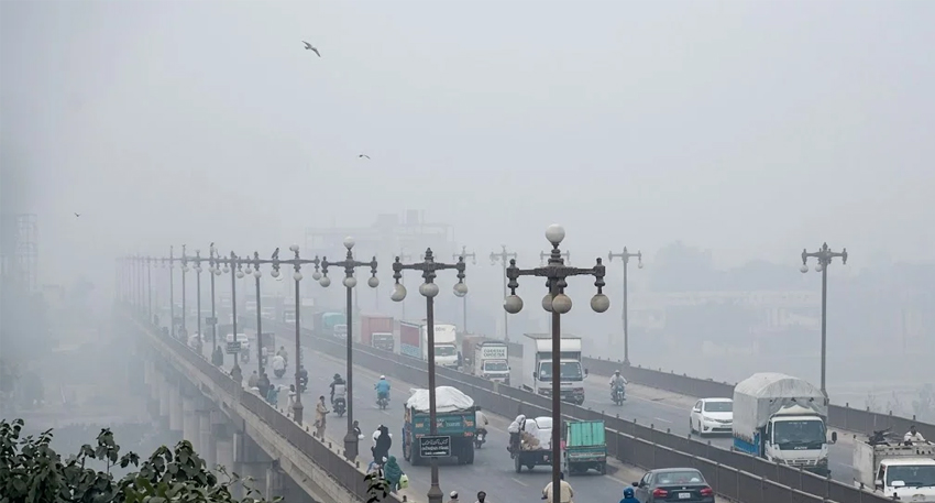 Traffic on a foggy bridge in Punjab under a hazy, heavily polluted sky.