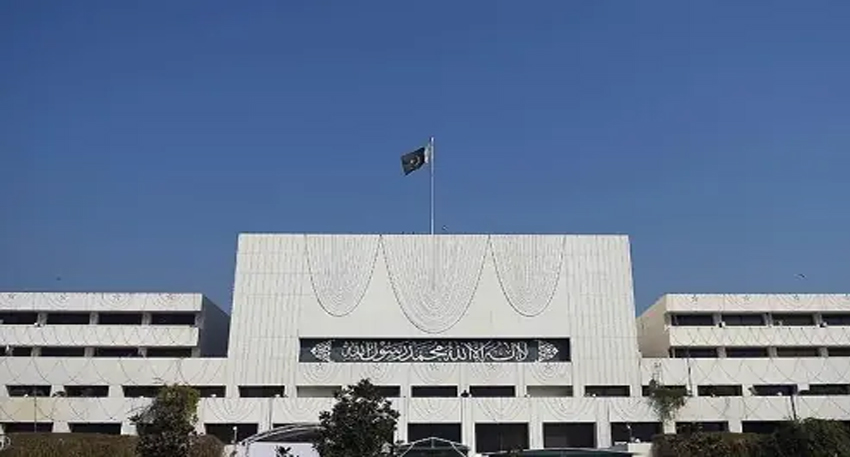 Parliament House building in Islamabad under a blue sky with the Pakistani flag flying.