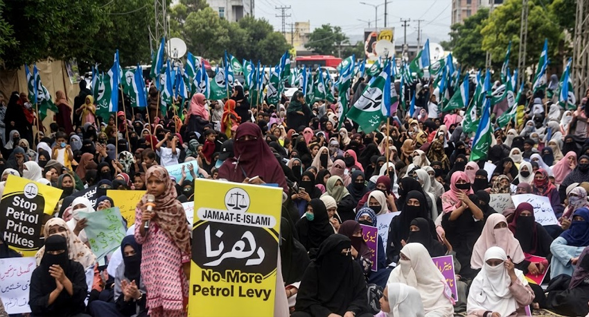 Women wave flags and hold anti-inflation signs at a Jamaat-e-Islami sit-in.