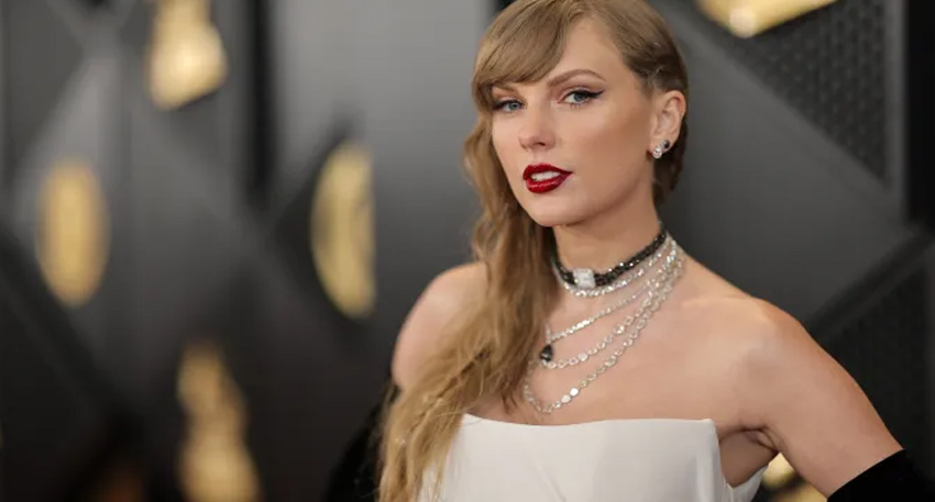 Taylor Swift with red lipstick wearing layered diamond necklaces and a white dress at the Grammys.